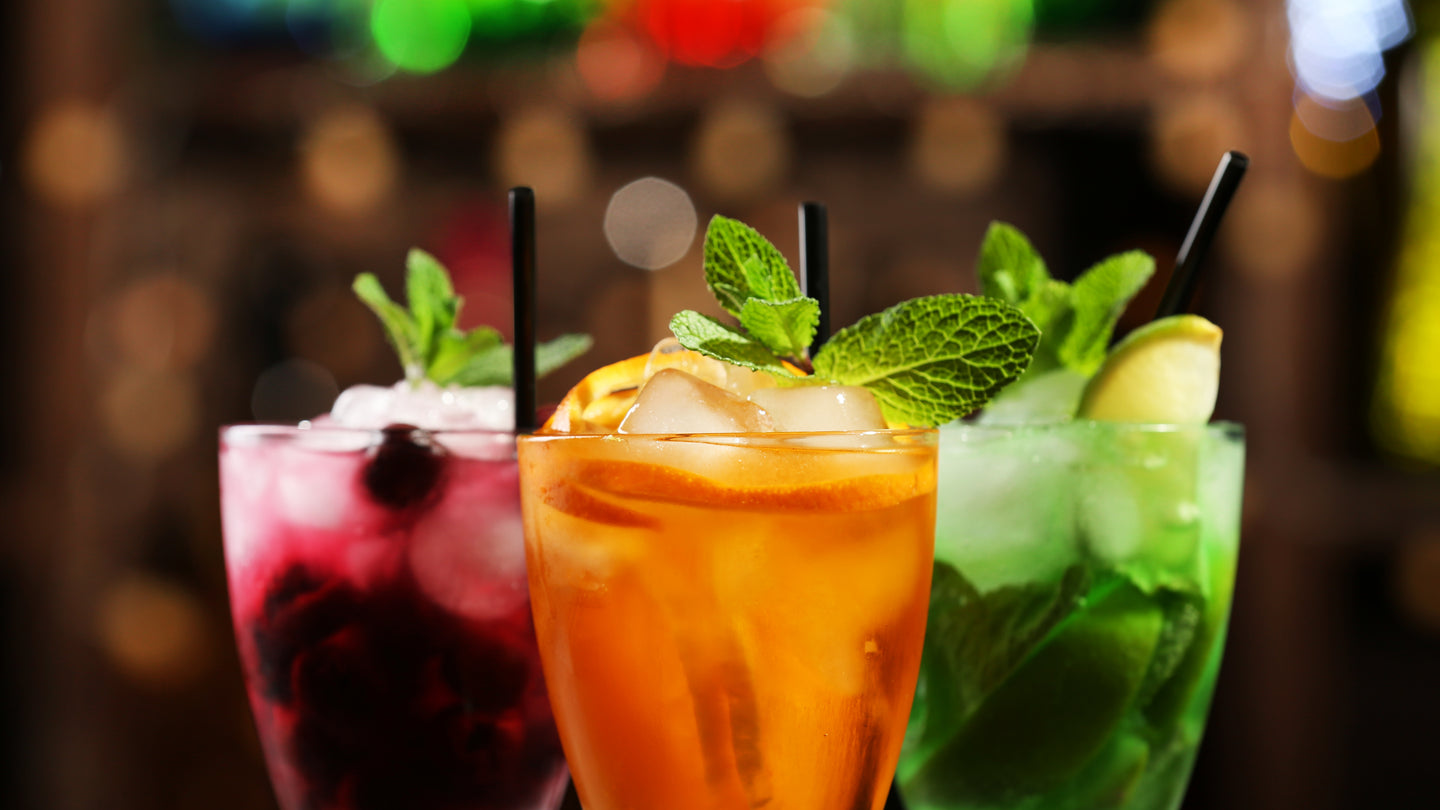 Three mixed drinks with cherry, orange and lime